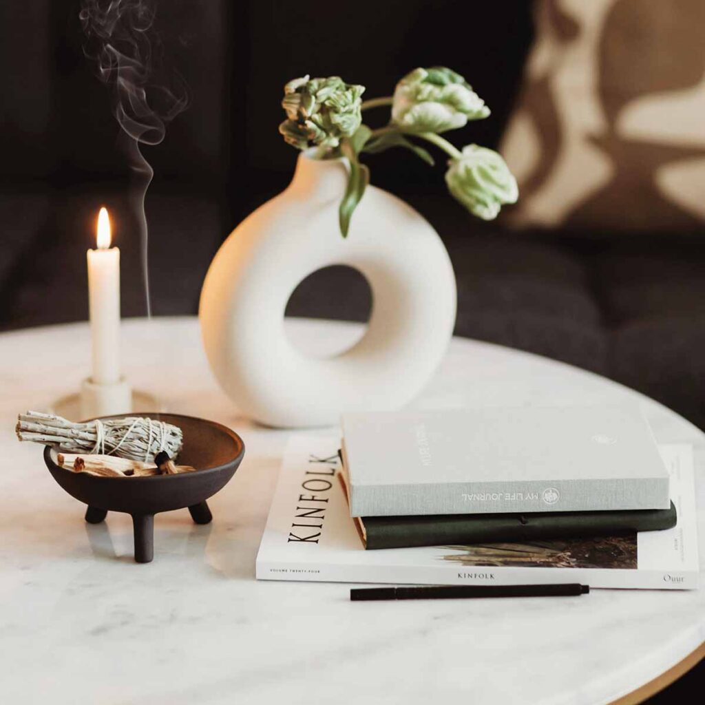 Stilvolles Interior-Styling mit Coffee Table Books, Kerze, Keramikvase und warmem Licht für eine atmosphärische Raumgestaltung