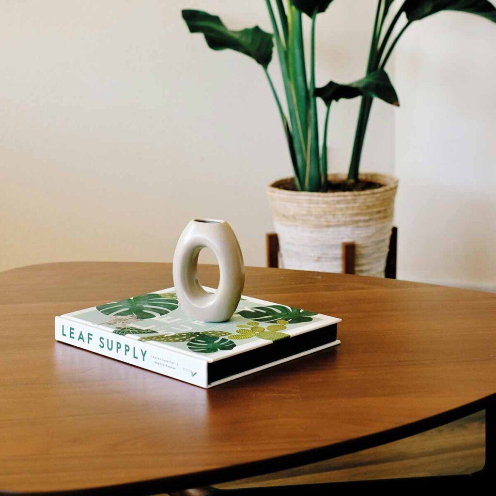 Coffee Table Books, Keramikvase und Kerzenlicht auf Marmortisch in warmer Interior-Atmosphäre